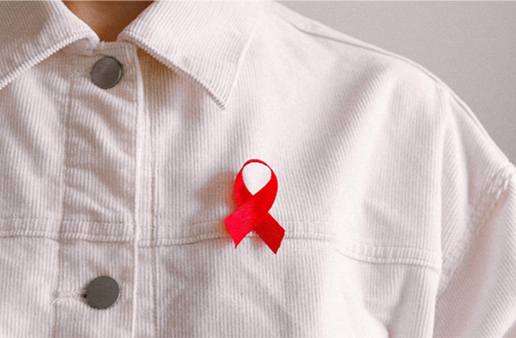 photo - closeup of someone wearing a red AIDS awareness ribbon