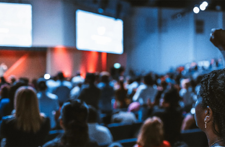 photo - a crowd looks towards a screen at a presentation