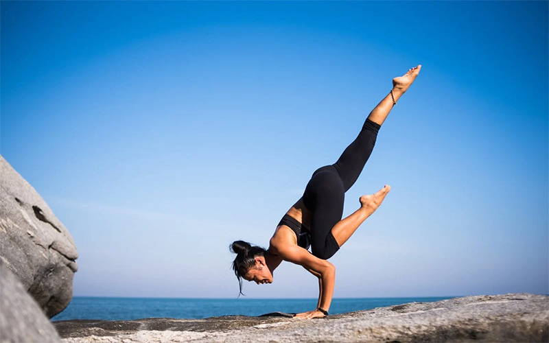 photo - a woman doing yoga at the beach