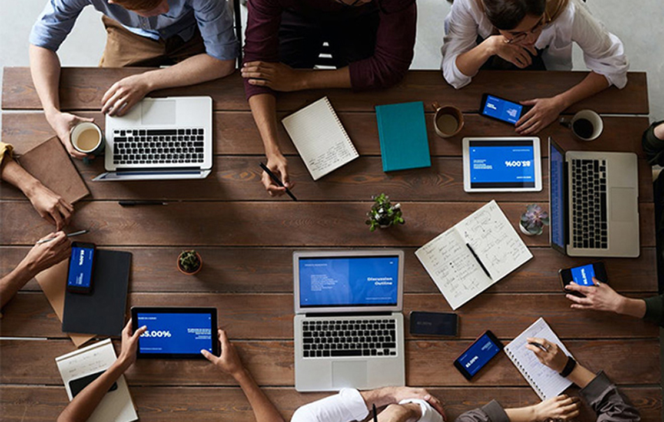 Photo - a group of people meeting at a wooden desk, seen from above